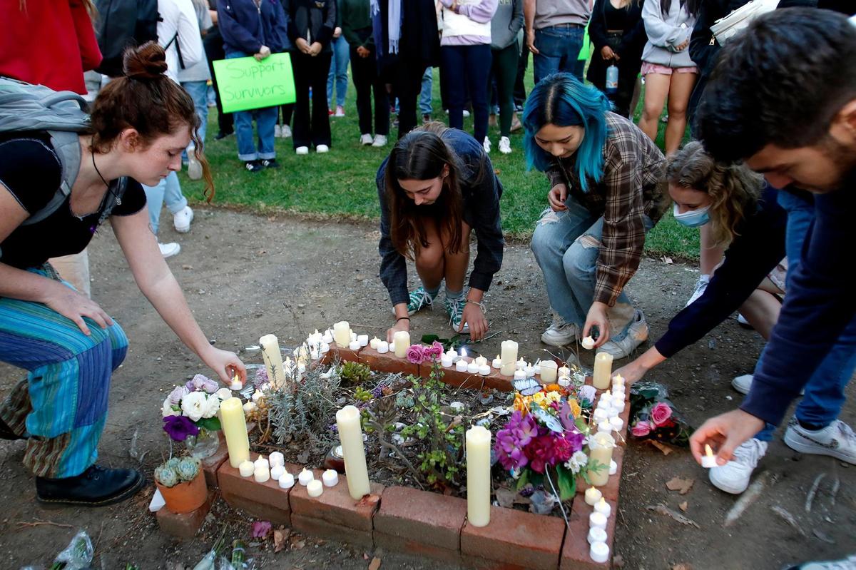 Attendees, friends and family place a safe candle,. flowers and mementos around a tree for Kristin Smart. A vigil organized by Cal Poly Safer, a group that focuses on education and prevention of sexual and gender-based violence. for Kristin Smart was held on the Cal Poly Campus Friday evening, Oct. 21, 2022. (Laura Dickinson, The Tribune, San Luis Obispo).