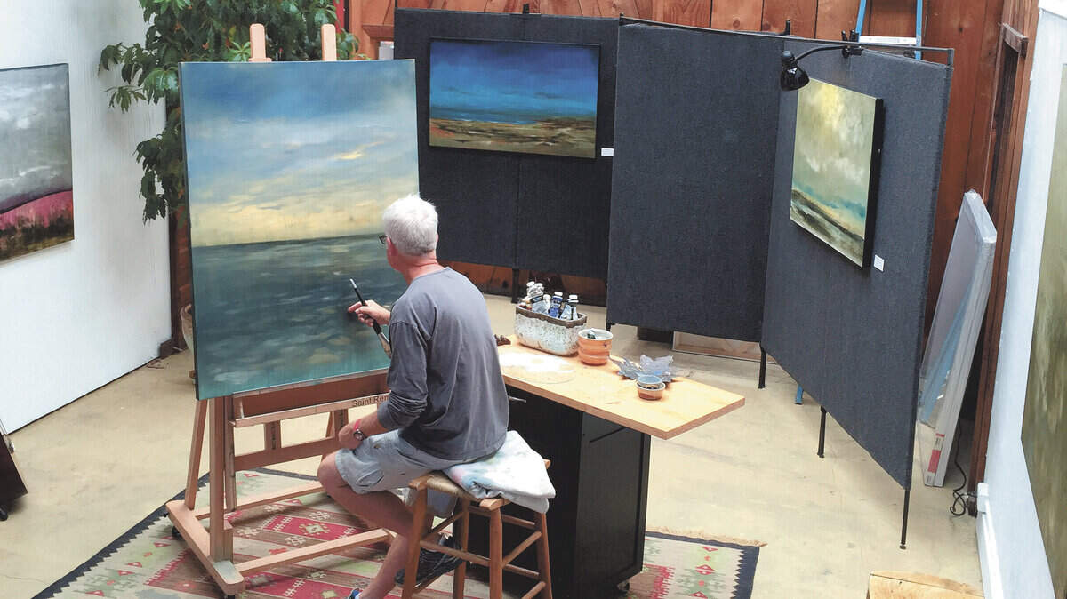 Patrick Dennis works on a painting in his gallery.