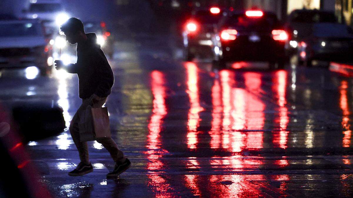 Pedestrian runs across Chorro Street with a food order as rain falls in downtown San Luis Obispo on the evening of Feb. 10, 2026.