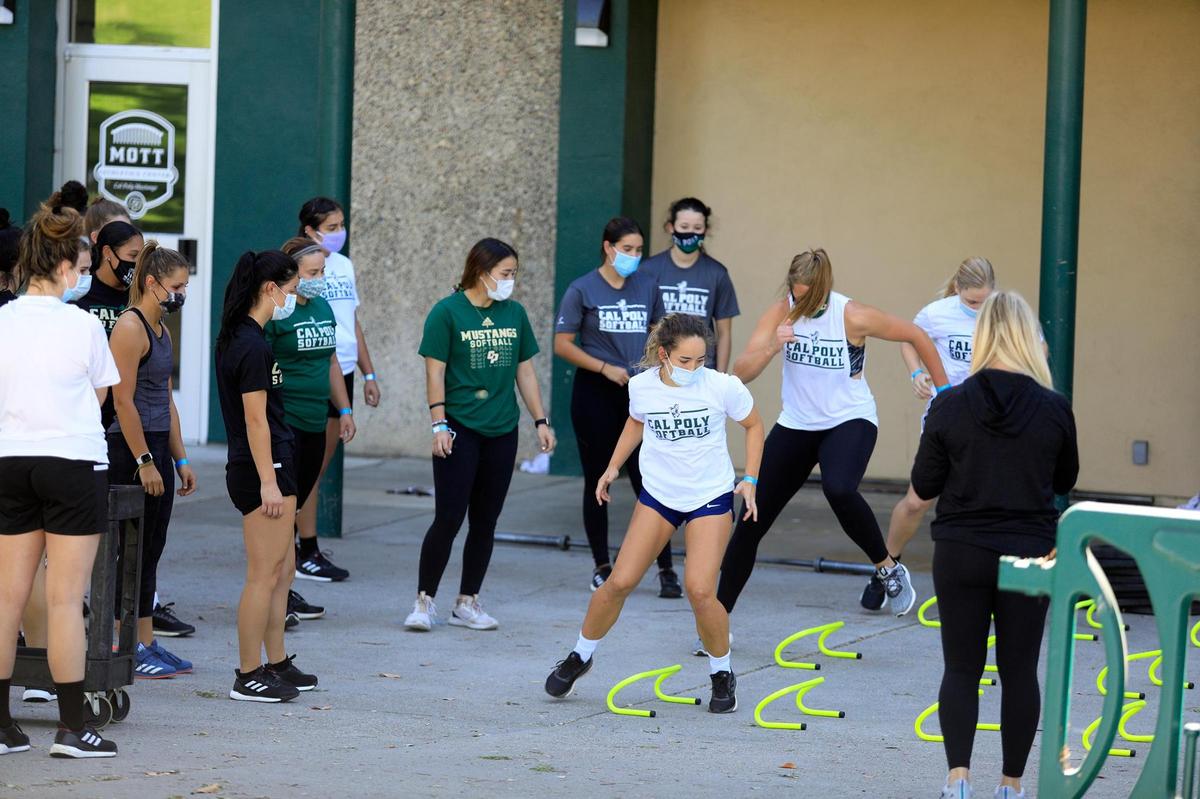Masked members of the Cal Poly softball team practice in front of Mott Gym in September.