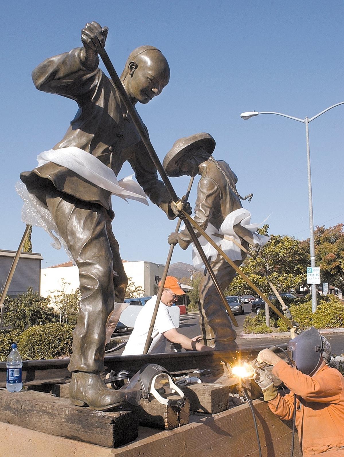 Allen Root welds and David Curry places concrete as they work to install the “Iron Road Pioneers” sculpture by Elizabeth MacQueen near the railroad station in San Luis Obispo on Oct. 17, 2002. The sculpture honors the Chinese contribution to California through their construction of railroads.