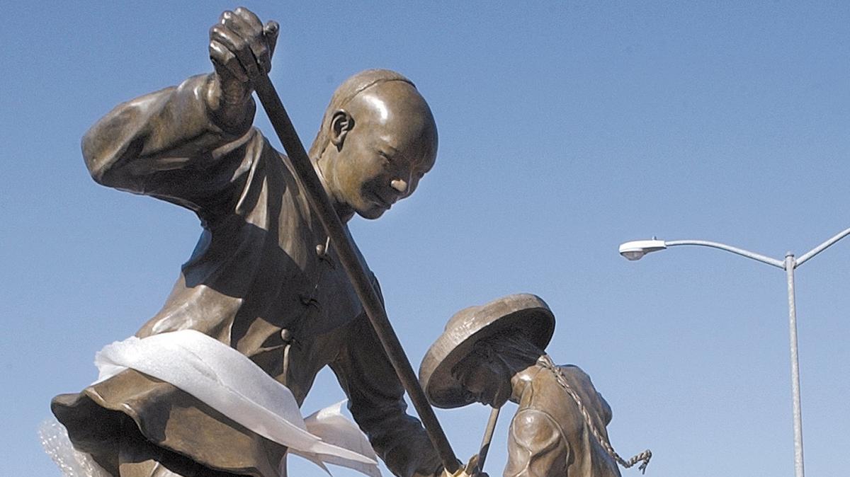 Allen Root welds and David Curry places concrete as they work to install the “Iron Road Pioneers” sculpture by Elizabeth MacQueen near the railroad station in San Luis Obispo on Oct. 17, 2002. The sculpture honors the Chinese contribution to California through their construction of railroads.