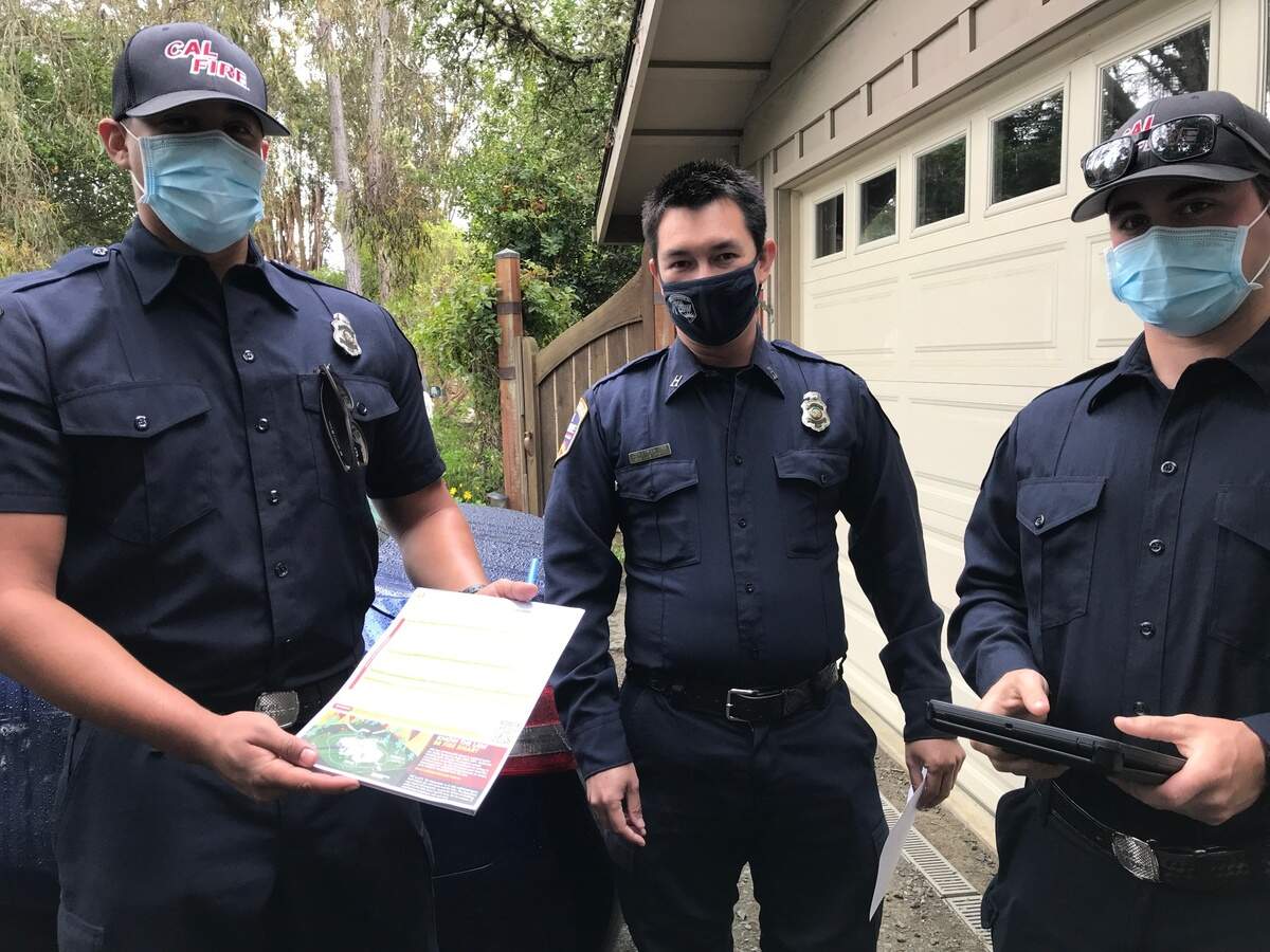 From left, Cal Fire firefighter Josia Martinez, forestry expert John Gee and firefighter Chris Laethem present columnist Kathe Tanner with her “Notice of Defensible Space Inspection” on May 17. The document details actions that she must take to help protect her Cambria home and property from wildfire.