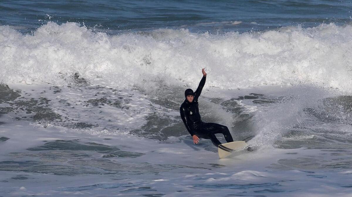 A lone surfer carves a wave near Morro Rock, Monday, Feb. 19, 2024, after a storm slammed San Luis Obispo County on Sunday night, bringing with it rising creeks and rivers and at least one swift water rescue.