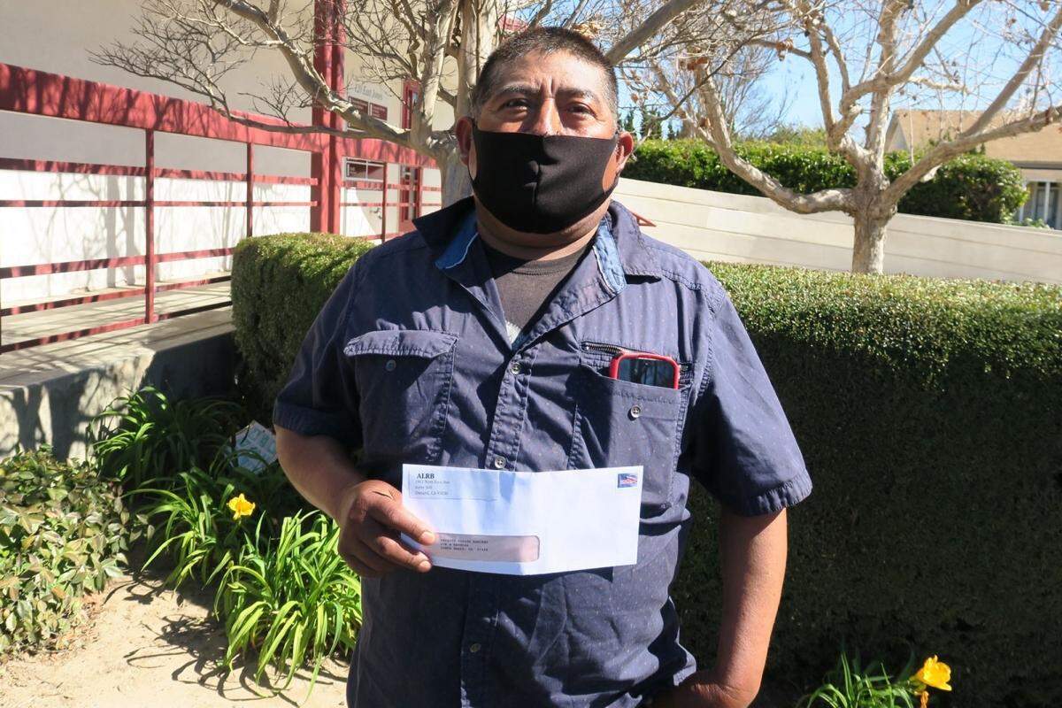 A farm worker holds up a check from a share of an informal settlement agreement between Rancho Laguna Farms and the California Agricultural Workers Board.