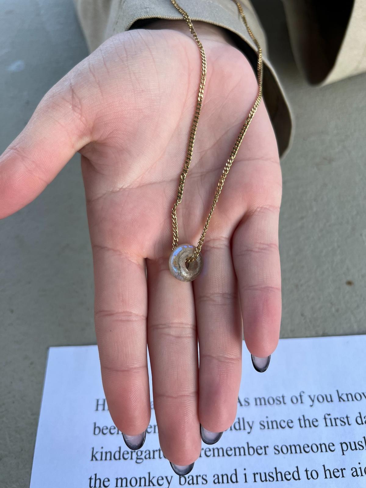 Reign holds a necklace that contains Reidly’s ashes over a copy of the speech she read at her friend’s memorial service.