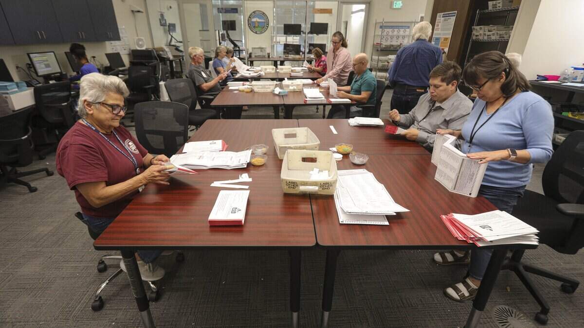 Temporary election workers Fochelle Friedman, left, Jesus Hurtado and Midori Feldman inspect mail-in ballots for damage or stray marks that would stall machine counting during the 2026 primary vote count on June 10, 2026.