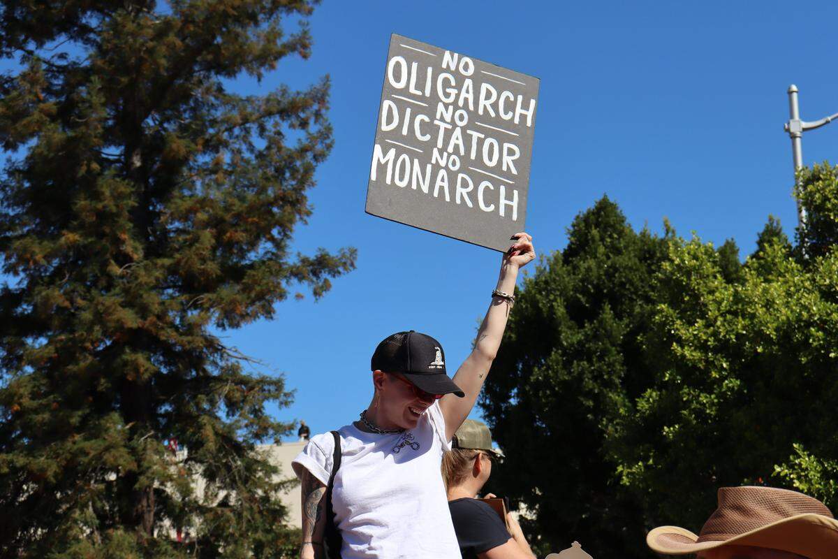 A protester holds up a “No Kings” sign at the Oct. 18 rally in downtown San Luis Obispo.