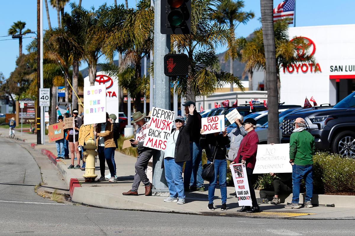 Dozens of people demonstrated outside the Tesla dealership in San Luis Obispo on Saturday, Feb. 8, 2025. They eventually walked from Calle Joaquin to Los Osos Valley Road.