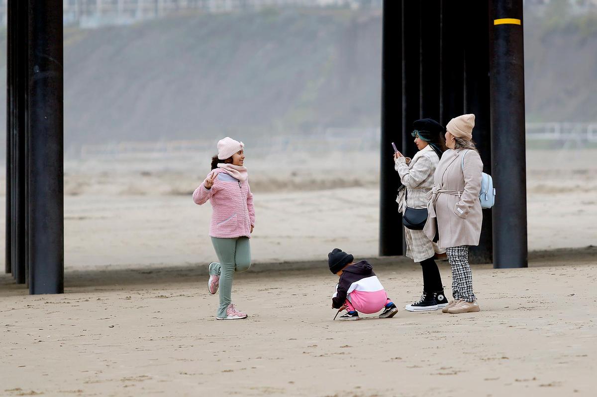 A family takes photos near the pier in Pismo Beach. Winds there were gusting up to 30 mph late Saturday morning, Dec 31, 2022.