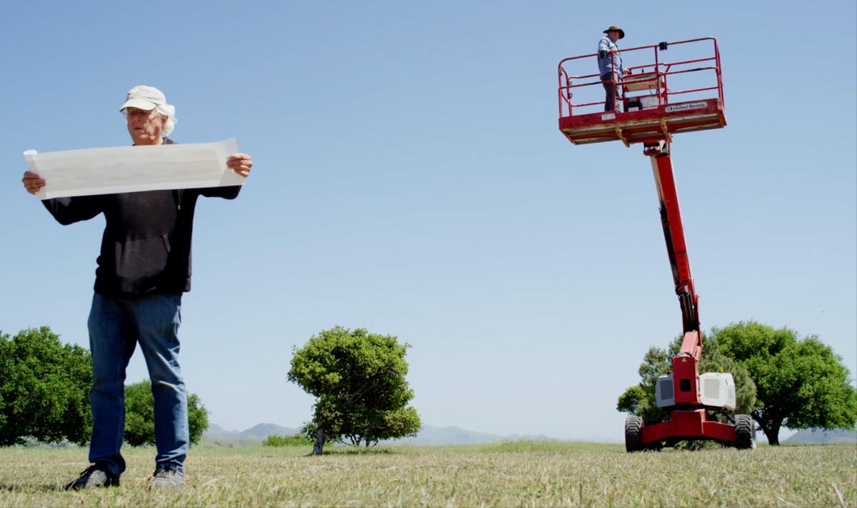 Brian Lawler examines a 1930 panoramic image of San Luis Obispo from atop Terrace Hill on April 17, 2021, as he recreates the historic image captured by Frank C. Aston. Behind him is the lift he would use to reach the proper height of the original photo. The top of Terrace Hill was removed in the 1940s to provide gravel for the construction of Highway 101.