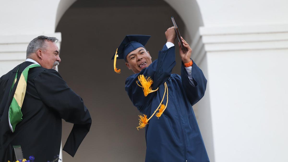 Luke Resty-Catacutan Montoya celebrates with a golf swing as principal Mike Susank smiles. Mission College Prep awarded diplomas to 69 graduates on the steps of Mission San Luis Obispo on May 31, 2024.