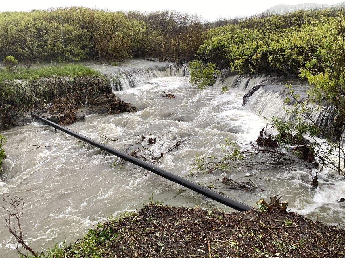 Water rushes under an exposed gas main in Old Creek near Studio Drive in Cayucos on Tuesday, March 14, 2023.