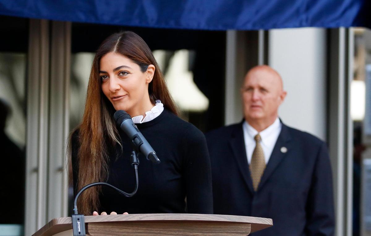 The new Katcho Achadjian Government Center sign was unveiled in a ceremony Friday, Oct. 20, 2023, in front of the former San Luis Obispo County Government Center. Achadjian’s daughter Nyri speaks to the crowd before the blue cloth was removed to reveal the sign.