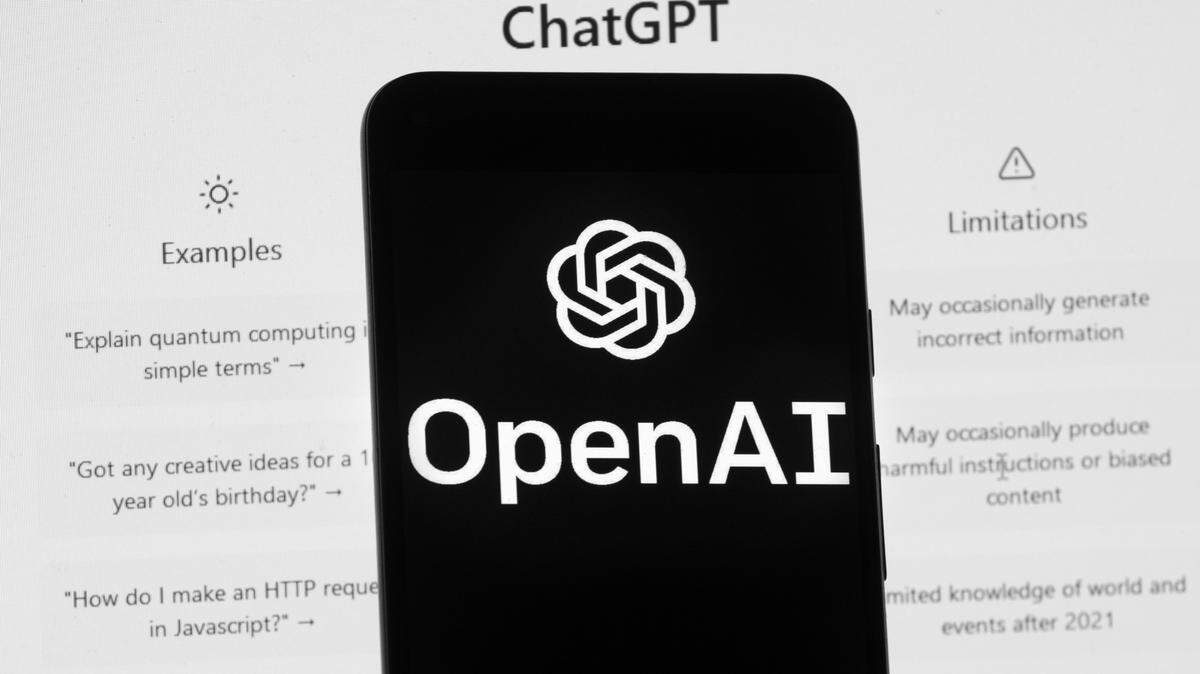 The OpenAI logo is seen on a mobile phone in front of a computer screen which displays the ChatGPT home Screen, on March 17, 2023, in Boston. Tribune columnist Linda Lewis Griffith asked the chatbot to write a column about happiness.