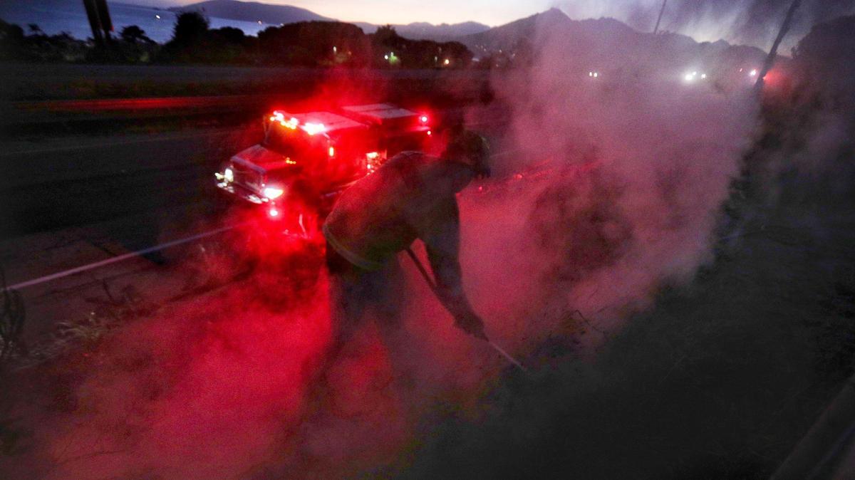 Marcus Anguiano works on hotspots along Highway 101 after sunset. A wind driven brush fire quickly moved south along Highway 101 along the Shell Beach straits and into Pismo Beach.