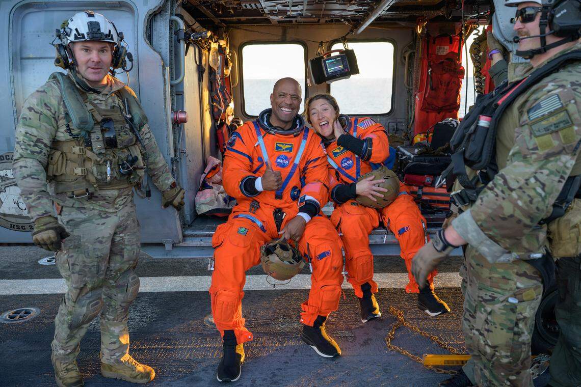 NASA astronauts Victor Glover, Artemis II pilot, left, and Christina Koch, Artemis II mission specialist, are seen sitting on a Navy MH-60 Seahawk from Helicopter Sea Combat Squadron (HSC) 23 on the flight deck of USS John P. Murtha after they were extracted from their Orion spacecraft after splashdown, Friday, April 10, 2026, in the Pacific Ocean off the coast of California.