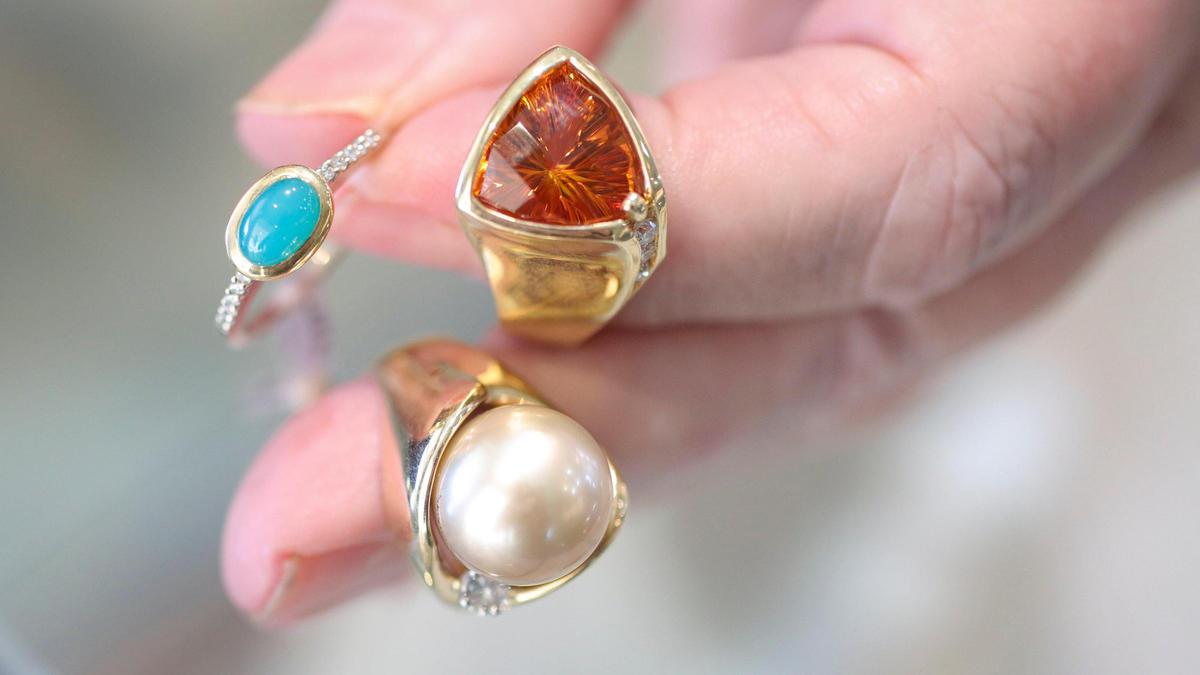 Claudia Alexander-Denny holds three rings she designed at Alexander-Denny Jewelry Studio in Cambria, from left, chrysocolla with 18-carat gold and diamonds, citrine with 18-carat gold and diamonds, and Tahitian pearl with 18-carat gold and diamonds.