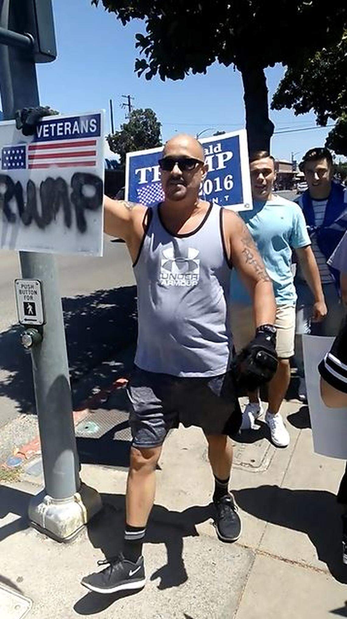 Todd Harmon, father of former Cal Poly wrestling recruit Bronson Harmon, carries a pro-Trump sign as he leads a counter protest in Modesto on June 30.