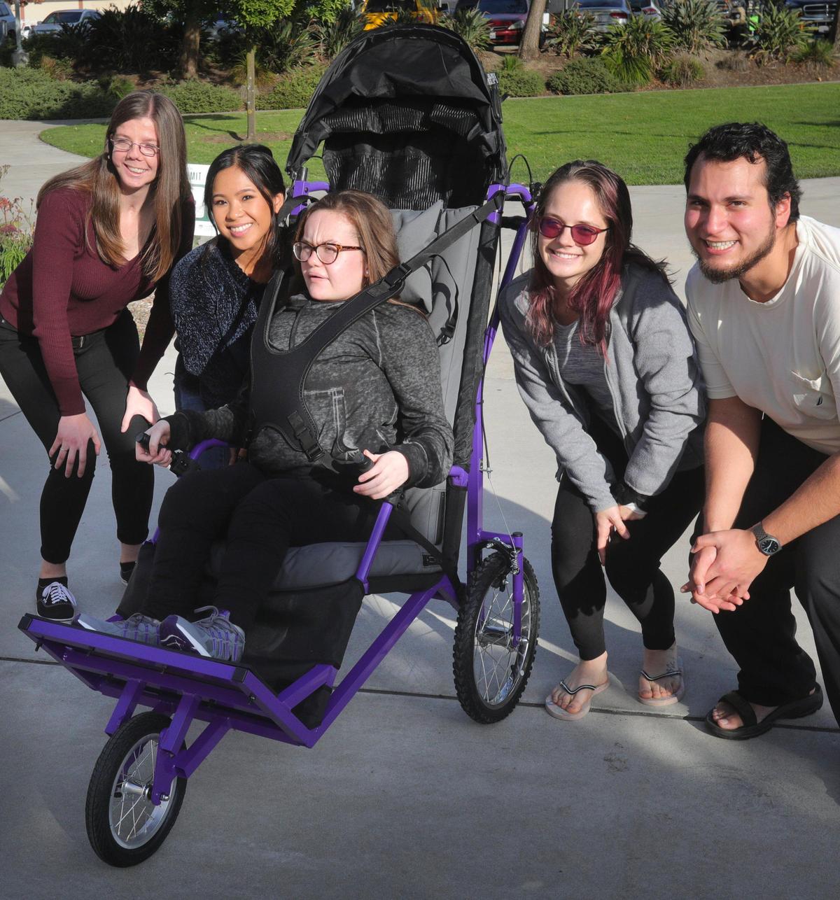 Cal Poly engineering students, from left, Kathryn Mangiaracina, Megan Guillermo, Erin Wint and Abdullah Sulaiman presented a jogger they designed and built to Katie Robinson, 17, of Fresno on Friday. It will allow her to join her father Edward Robinson when he runs.