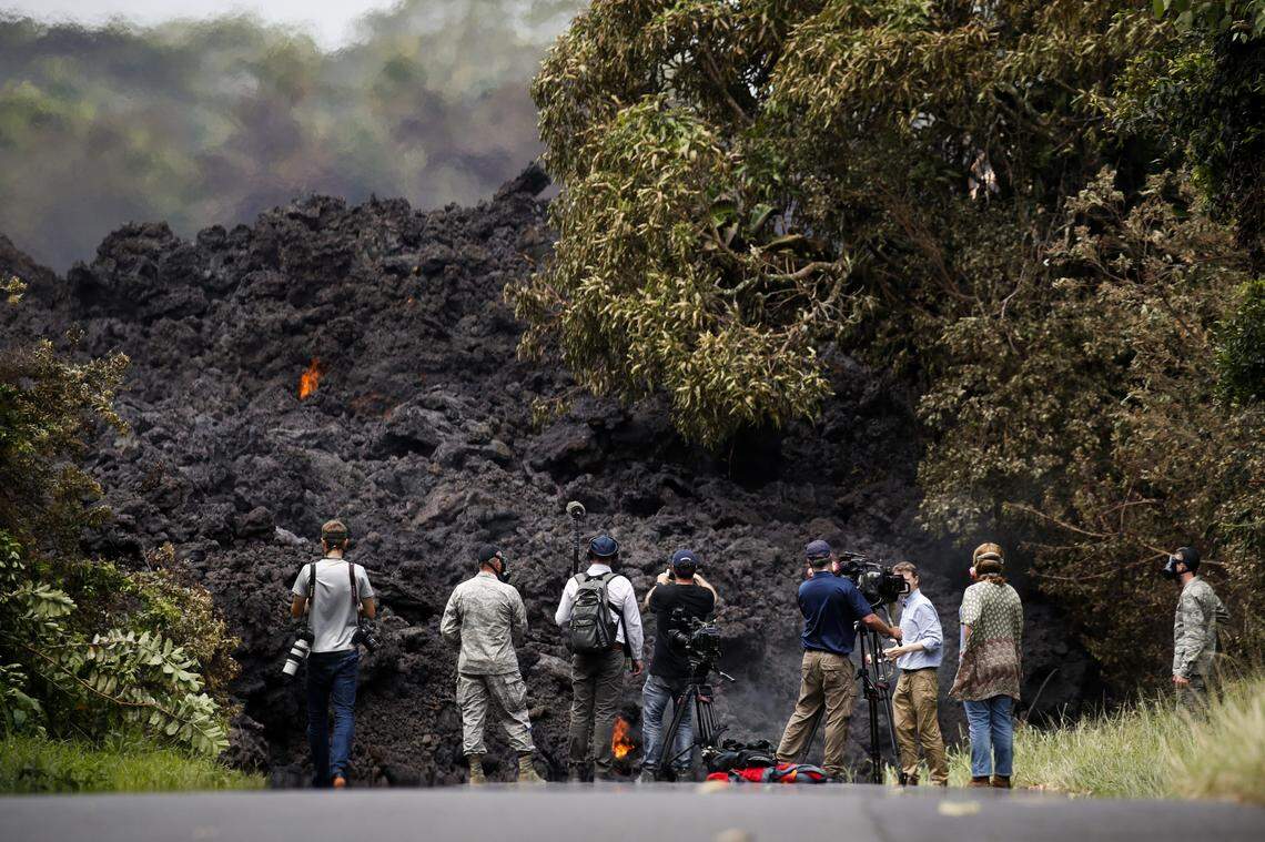 Members of the media record a wall of lava entering the ocean near Pahoa, Hawaii, Sunday, May 20, 2018. Kilauea volcano, oozing, spewing and exploding on Hawaii's Big Island, has gotten more hazardous in recent days, with rivers of molten rock pouring into the ocean and flying lava causing the first major injury.