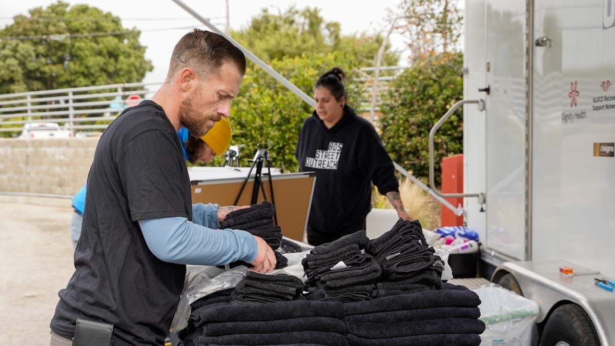 A volunteer lays out towels for clients of 805 Street Outreach’s new shower program, which offers showers and hygienic products to homeless residents of Morro Bay, on Feb. 5, 2024. The program will operate from noon to 3 p.m. in the Morro Bay Library parking lot on the first and third Mondays of the month.