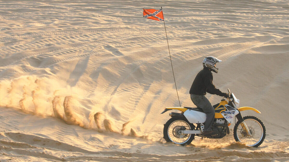 A motorcycle kicks up sand at sunset at the Oceano Dunes.