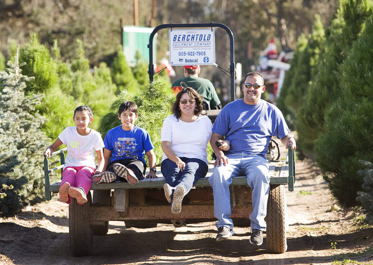Pedro Valencia, right, his wife Teresa, and their children David and Andrea of Santa Maria get a ride with their freshly cut Christmas tree at Holloway’s Christmas Tree Farm in Nipomo.