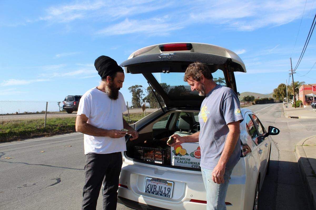 The Avocado Shack owner Michael Wolfe and Encino Grande Ranch manager Kephus Neuhs “talk numbers” just outside the Morro Bay produce market while customers browse the shelves inside.