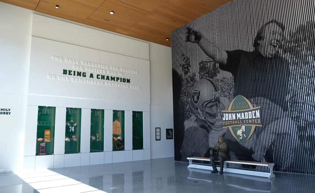 The foyer of Cal Poly’s newly unveiled John Madden Football Center features a ceiling-high mural of the famous alum, behind a bronze statue that visitors are invited to sit next to.