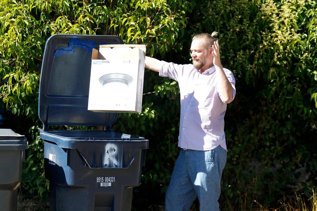 John Patrick, Atascadero, tosses an item to be recycled into a recycling bin in front of his home.