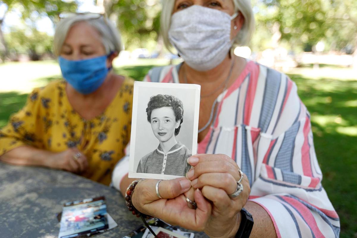 Lori Head, left, and Melinda Luce, both of Atascadero, show off a photo of their mother, Margery McGoff. McGoff died from coronavirus in July.