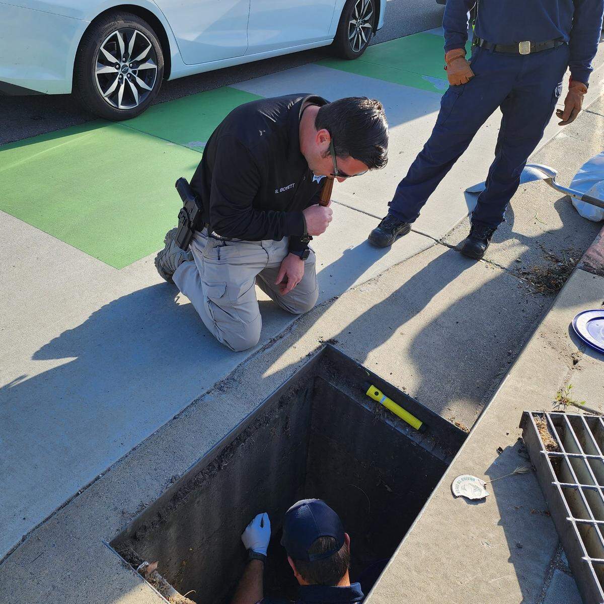 Paso Robles Police Sgt. Steve Boyett blows on a duck call to lure out one of 13 ducklings who fell into a storm drain at Niblick and Creston roads on April 13, 2023.