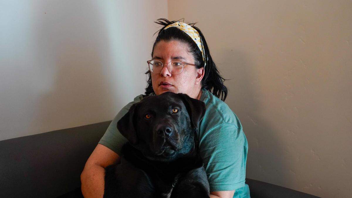 Kimie Brewer sits with Admiral the black Labrador mix in her Broad Street Place home March 12, 2024.