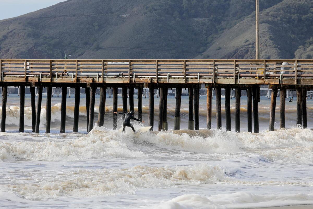 A surfer hits the waves in Avila Beach on Sunday, Dec. 11, 2022, following a powerful storm.