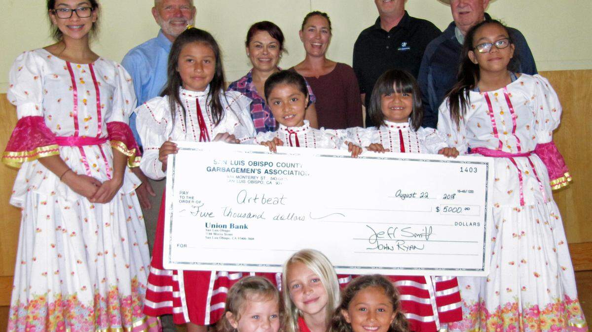 From left, are: adults in back of the check, Supervisor Bruce Gibson, Artbeat folklorico dance instructor Carmen Castillo, Artbeat founder/chairwoman Anna Griffith, Jeff Smith and John Ryan of Waste Connections; in the middle row, behind the check, are dancers Emma Sison, Yaretzi Loredo, Dulce Hernandez, Nicole Castillo and Sofia Sison. In front of the check are Gracie McGillivary, Arwen Griffith and Leyla Lopez.