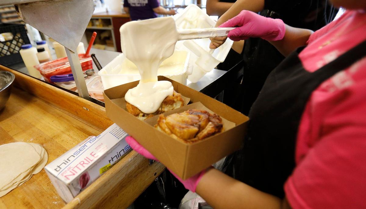 House-made icing is dolloped hot cinnamon rolls at Old West Cinnamon Rolls in Pismo Beach.