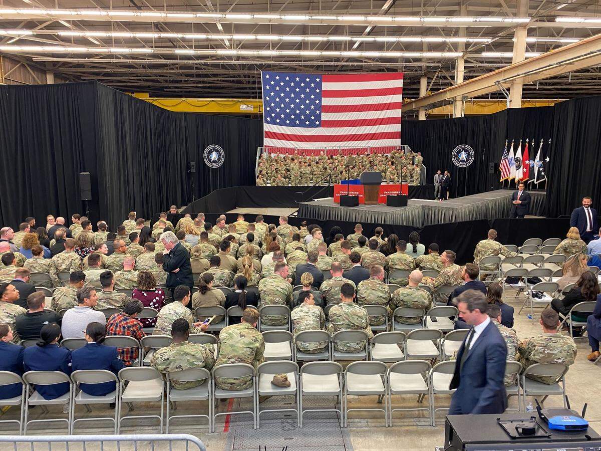 Military service members and others wait for U.S. Vice President Kamala Harris to speak at Vandenberg Space Force Base.