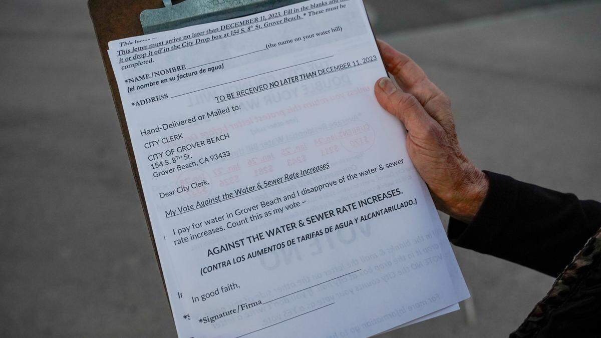 Grover Beach residents protest a proposed 112% water rate increase over the next five years, before the Grover Beach City Council meeting on Nov. 13, 2023. Some residents said they have started knocking on doors, encouraging their neighbors to write letters of protest against the project.