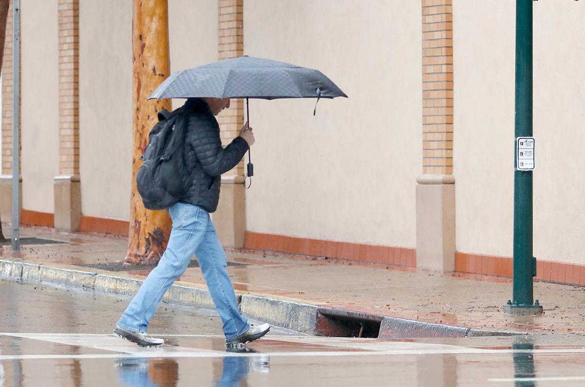 A person walks through the rain on Higuera Street in downtown San Luis Obispo on Thursday, Feb. 6, 2025. 