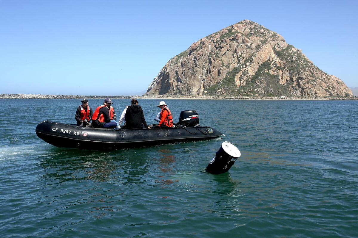 Cal Poly students took to the seas May 22, 2025, to test a prototype for a device aimed at harnessing the energy of waves to charge batteries. A U.S. Navy vessel floats past the Cal Poly’s Expeditionary Ocean Power Generator in the Morro Bay Harbor.