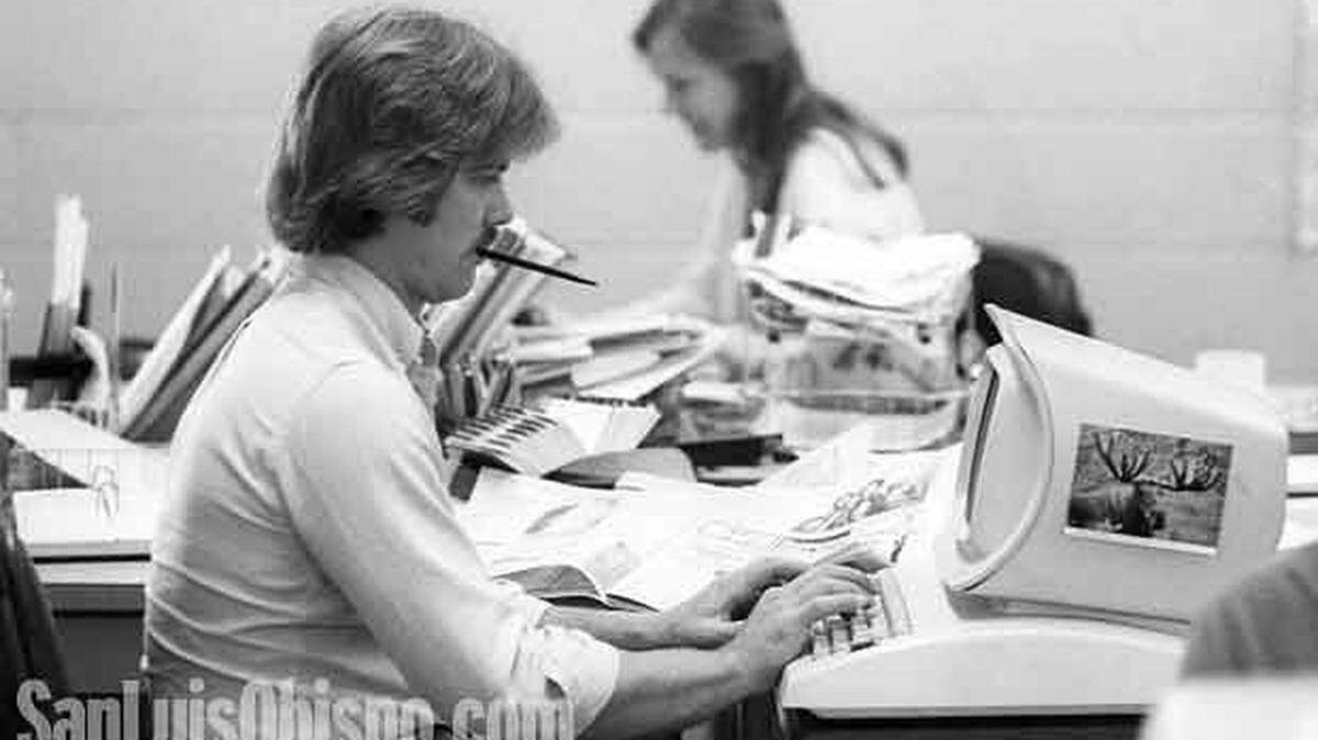 Photo from the 1982 Telegram-Tribune newsroom Dan Stephens foreground and Ann Fairbanks background. Images for a handbook. Tools of the trade, Rolodex of phone numbers, calendar day planner, reference books newspaper clippings, pen and paper. Moose postcard was purely for decoration.