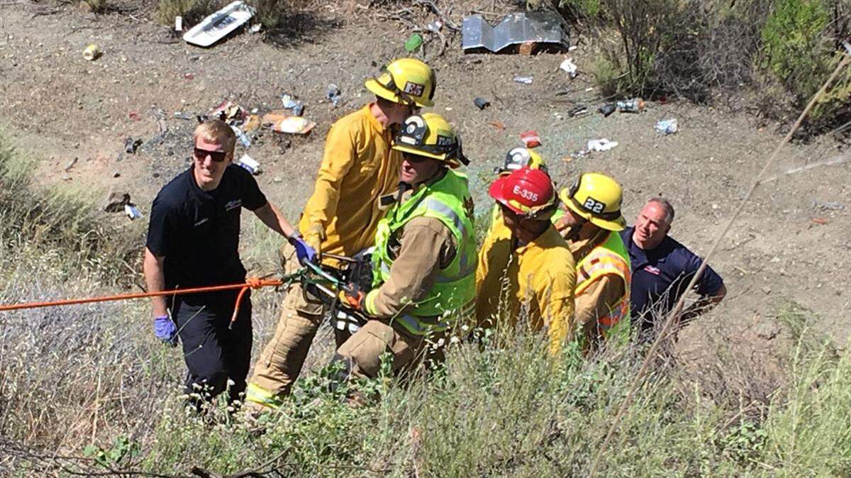 Rescuers carry an injured person up a hillside after a single-vehicle accident Sunday on Highway 166 east of Santa Maria.