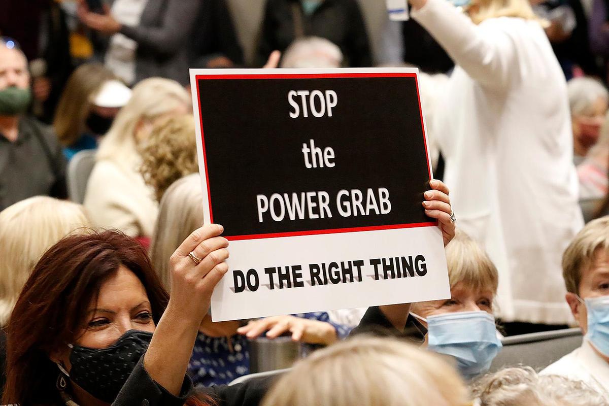 An attendee at a Board of Supervisors redistricting hearing on Friday, Nov. 19, 2021, holds up a sign that reads “Stop the power grab: Do the right thing.”