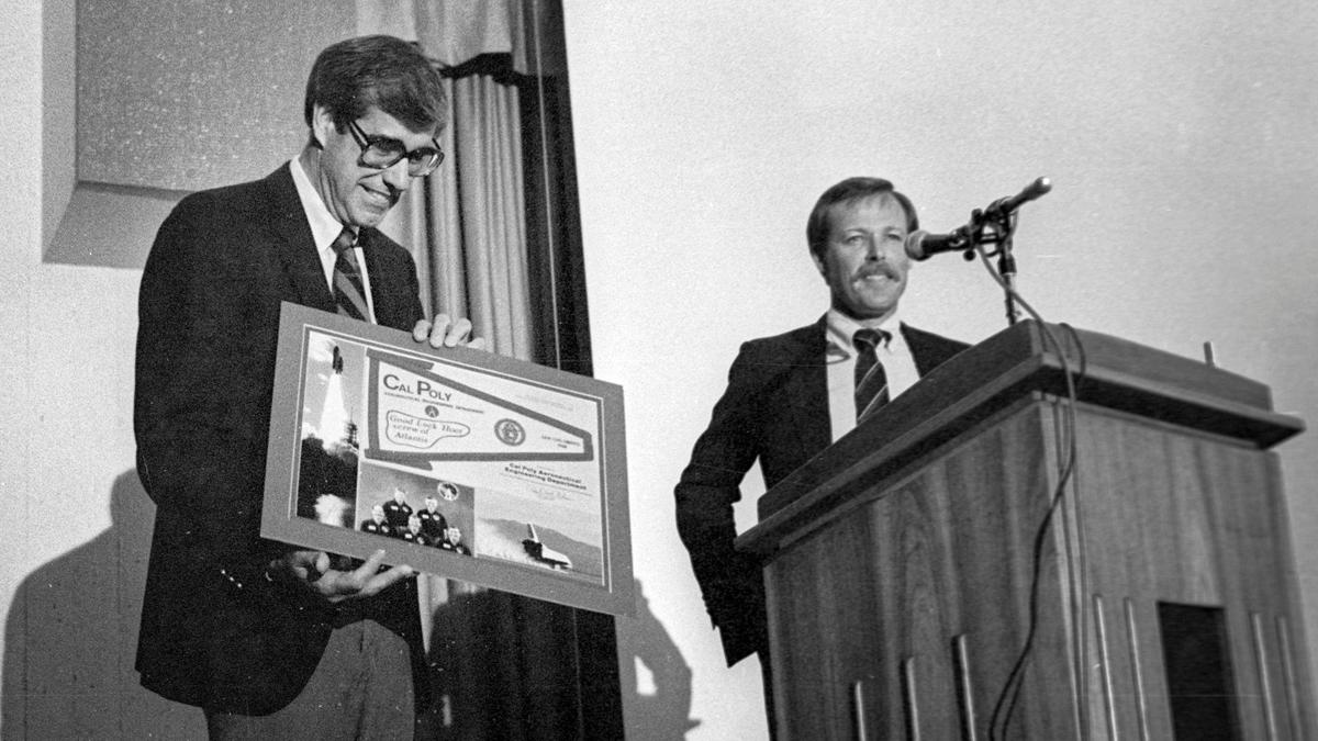 Cal Poly President Warren Baker, left, holds a framed memorabilia from alumni astronaut Robert “Hoot” Gibson on June 9, 1989.