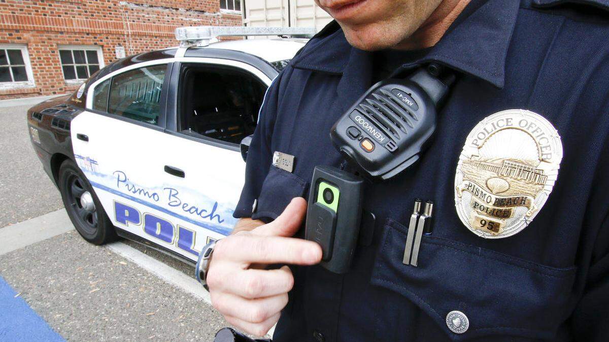 Pismo Beach police Officer Chris Siglin demonstrates the body camera worn by officers in the department. The camera's door slides open, revealing green, which means the camera is recording.
