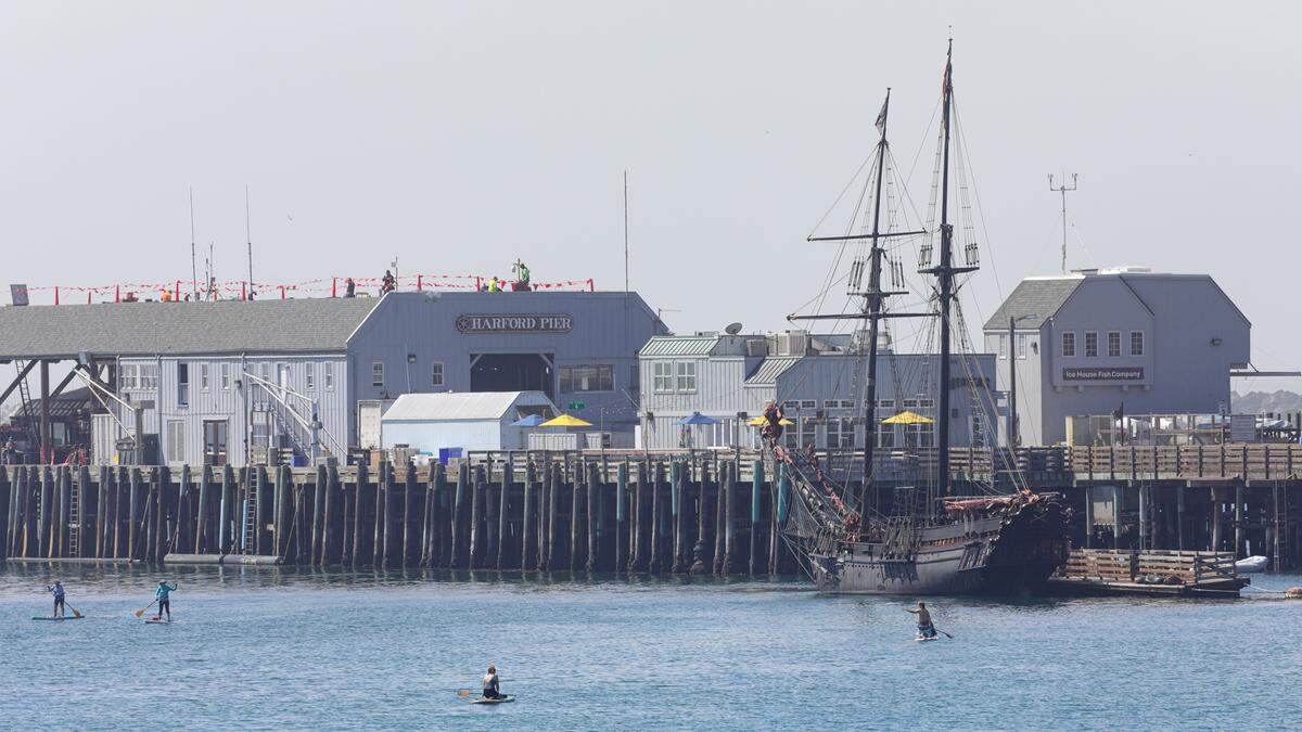 A flotilla of stand up paddlers have the ship Devil’s Gauntlet surrounded at Port San Luis in Avila Beach on May 24, 2022. The canopy at the end of the Harford Pier is undergoing a $250,000 refurbishing. It will look similar to the 1914 version of the structure when the shingles on the sides are replaced. Chris Munson, facilities manager with the Port San Luis Harbor District, said this is the first step in a larger rehabilitation of the west side of the pier. More information on the pirate ship temporarily docked at the port can be found at BuccaneerLeague.org.