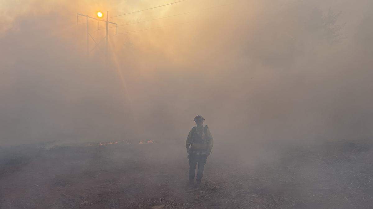 A firefighter walks through smoky conditions in the Smith River Complex fire burning along the California-Oregon border on Sept. 19, 2023.