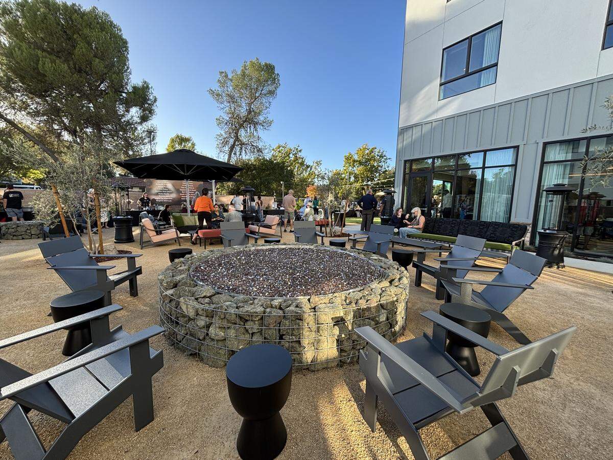 A large fire pit sits in the backyard area of Cambria Hotel Templeton-Paso Robles, with two more private fire pits on the sides of the lawn.