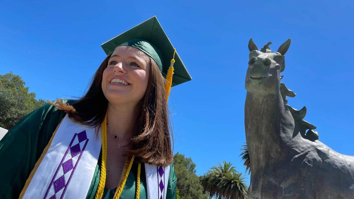 Lauren Tarica — aka Little Miss Cal Poly Grad — poses with the Mustang statue outside Spanos Stadium after her graduation on June 12, 2022.